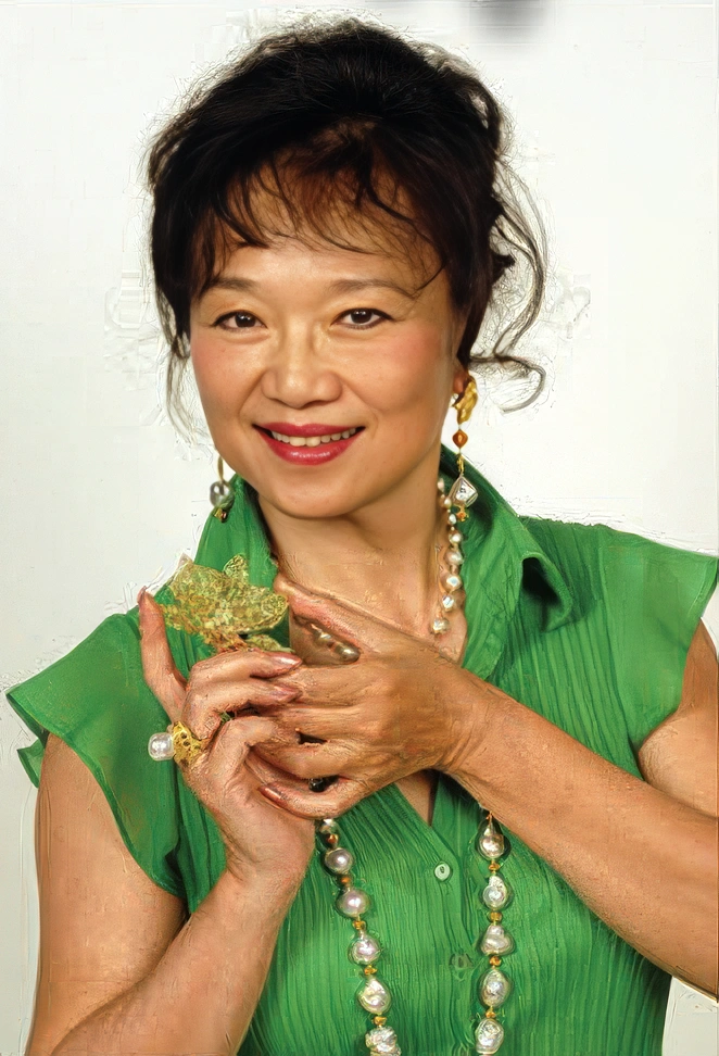 Kathy Chan wearing a green shirt holding a piece of jewelry she made.